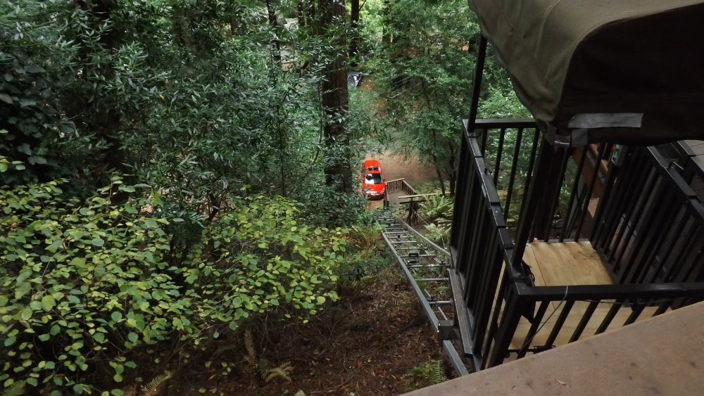 Ultra Hoist track descending through woods from a canopied upper landing